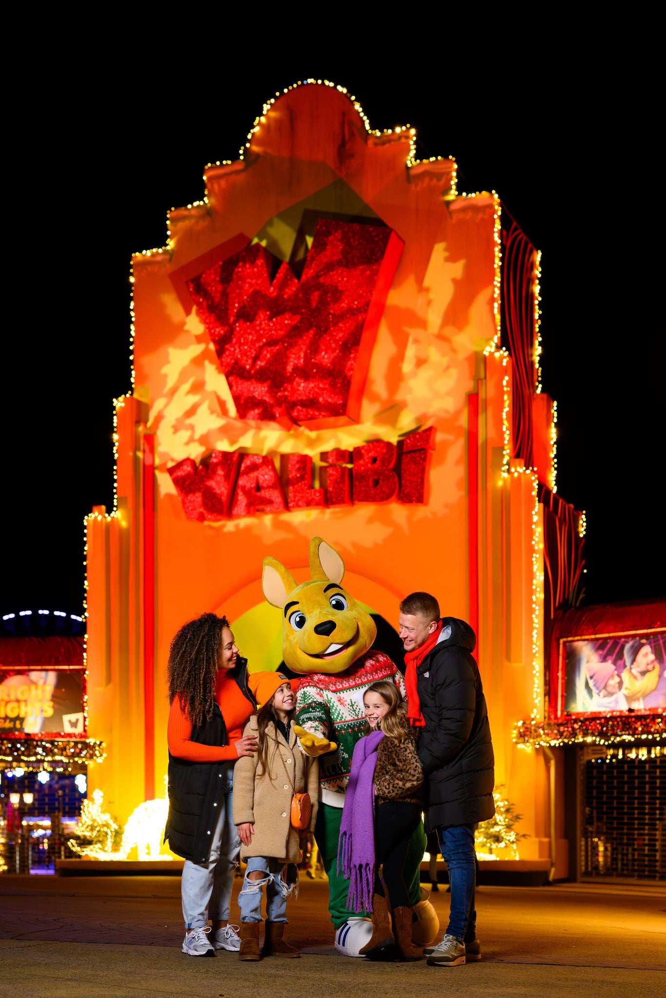 Een familie voor de ingang van Walibi Holland met de mascotte 